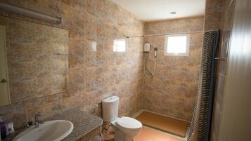 Une salle de bain avec un mur en marbre, un lavabo, des toilettes, une douche et une fenêtre.