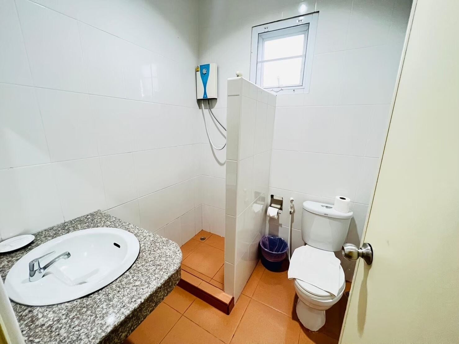 Un baño pequeño con lavamanos blanco, inodoro y zona de ducha.
