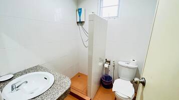 Un baño pequeño con lavamanos blanco, inodoro y zona de ducha.