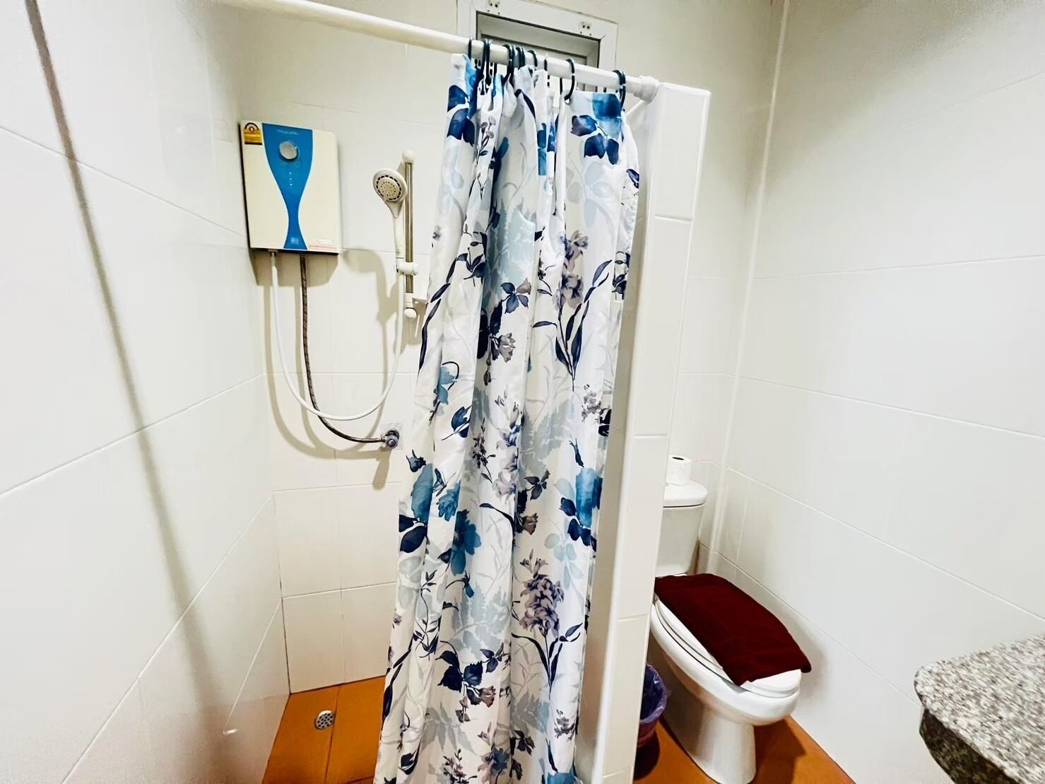 A bathroom with a shower curtain, a handheld showerhead, a toilet, and a bidet.
