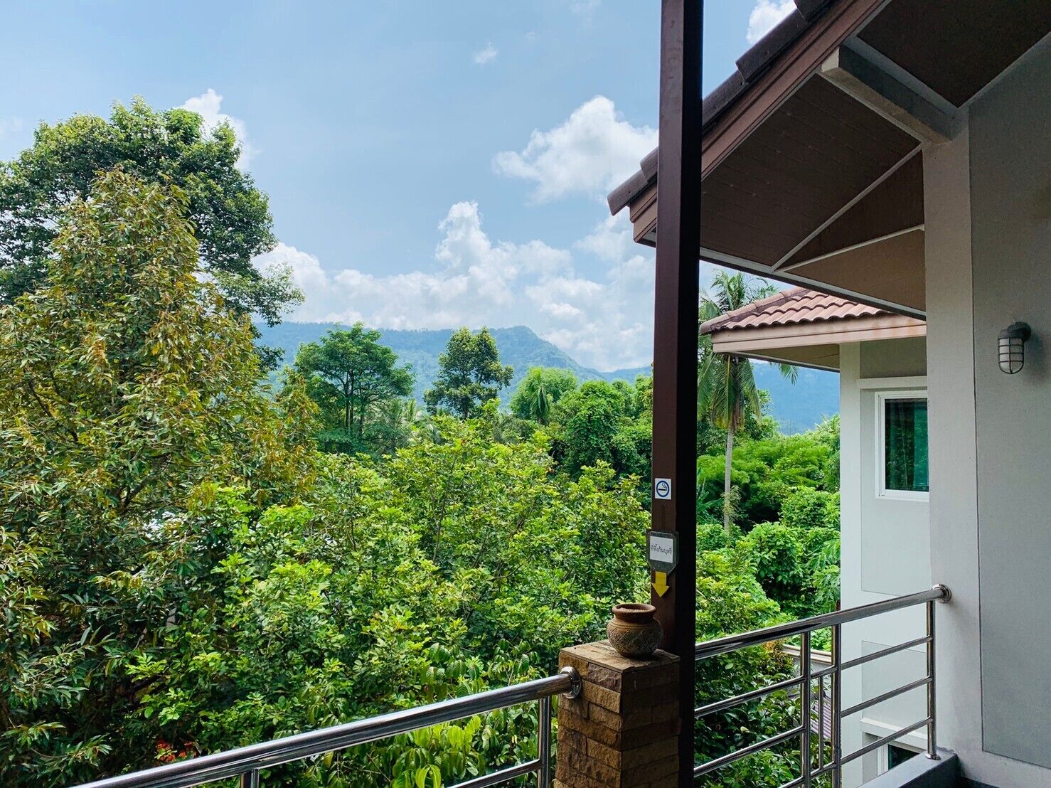 A balcony with a view of lush greenery and distant mountains.