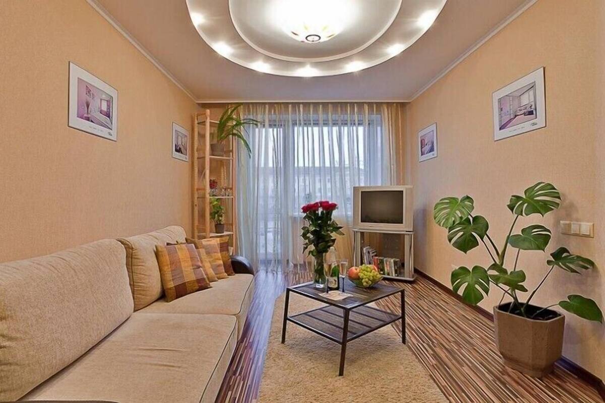 A living room with a sofa, coffee table, TV, and plants.
