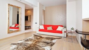 Uma sala de estar moderna com um sofá branco, um cobertor vermelho, um espelho grande e um tapete de pele.