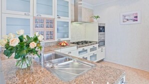 Uma cozinha moderna com bancadas de granito, eletrodomésticos de aço inoxidável e forno embutido.