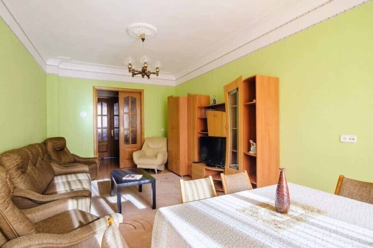 A living room with a sofa, armchairs, a coffee table, a TV, and built-in wooden shelves.
