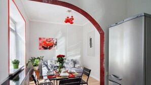 Uma área de refeições compacta com uma mesa posta para quatro pessoas, um sofá e uma geladeira.