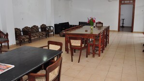 Un comedor espacioso con una larga mesa de madera, varias sillas y un ventilador de techo.