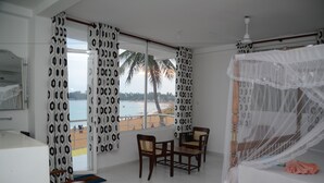 Un dormitorio con cama, una mesa, dos sillas y vista a la playa.