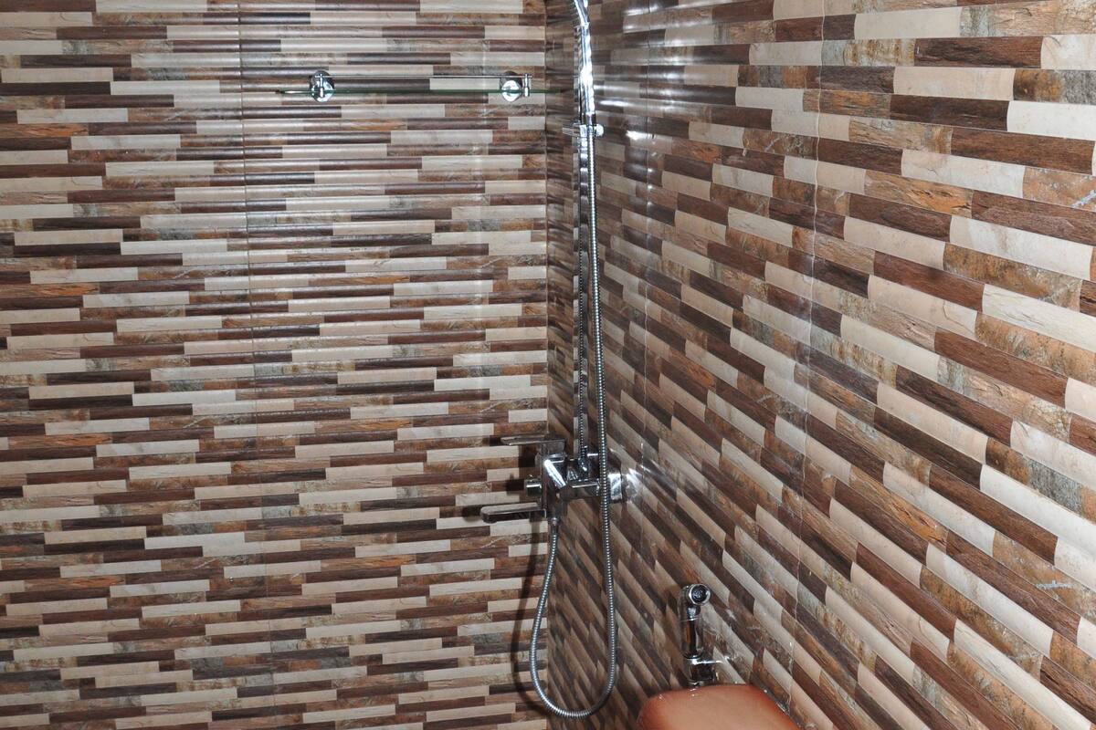 Un baño con pared de ducha azulejada, inodoro y ducha.