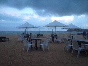 A beachside cafe with outdoor seating and umbrellas. - SURF UNA Beach Hotel (Unawatuna)