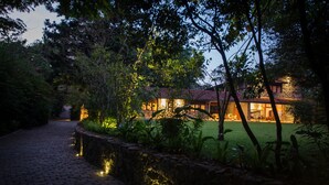 Un sendero que lleva a un edificio, con un muro de piedra a un lado y un césped bien iluminado.