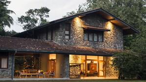 Una casa de piedra con un porche cubierto, ventanas amplias y un césped cuidado.