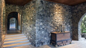 Un interior con paredes de piedra, un banco de madera y escalones que llevan a una puerta.