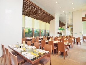 A spacious dining area with multiple tables and chairs, large windows with a view of greenery, and a modern ceiling design. - Winland 800 Hotel (Tsing Yi)