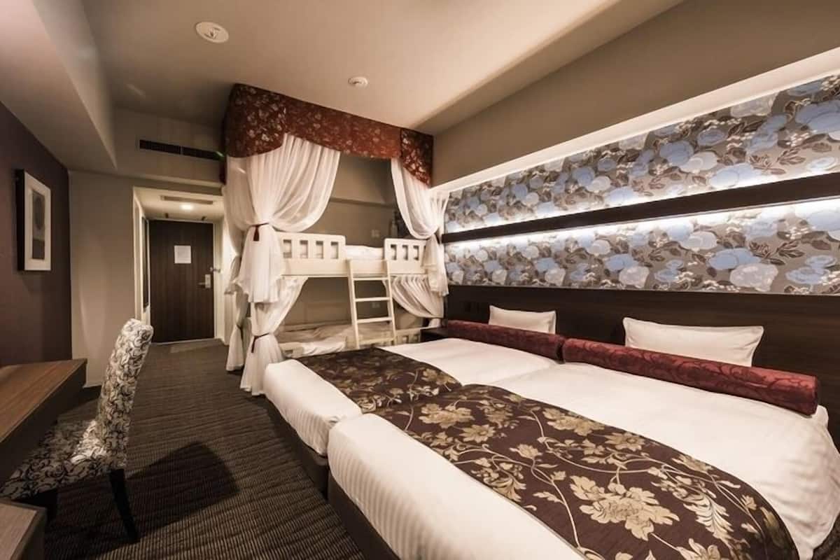 A hotel room with a large bed, a desk, a chair, and a wardrobe.