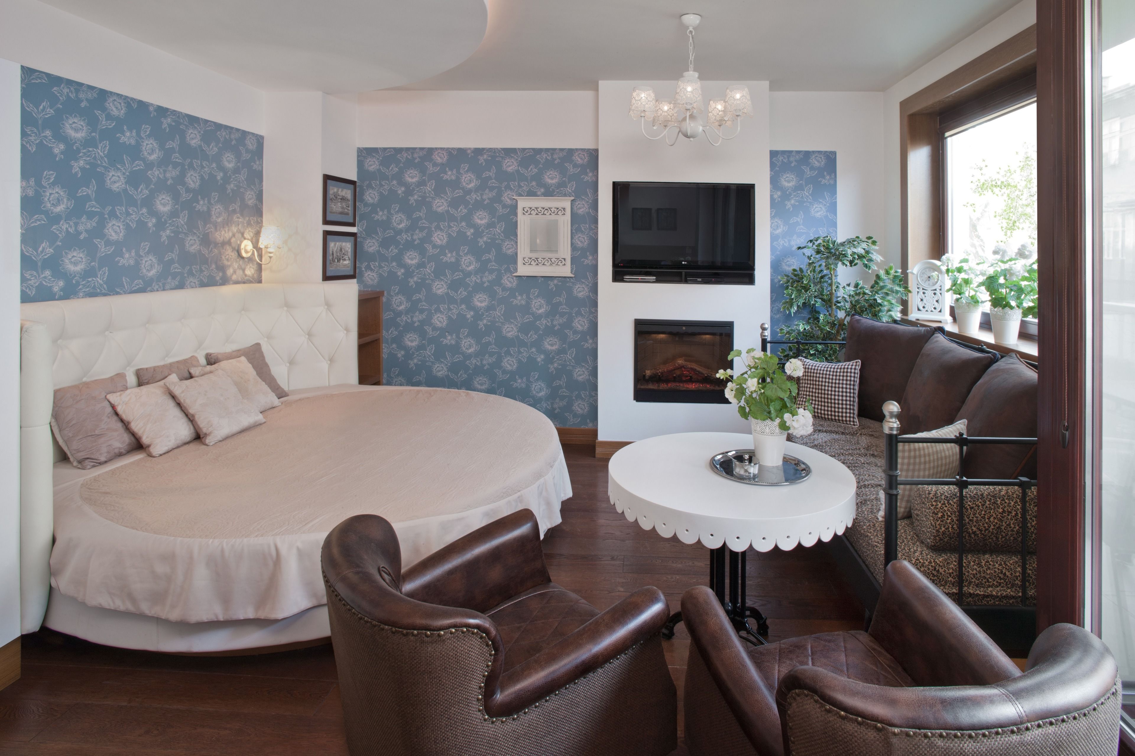 Un dormitorio con una cama grande, televisor, chimenea y zona de comedor con sillas y mesa.
