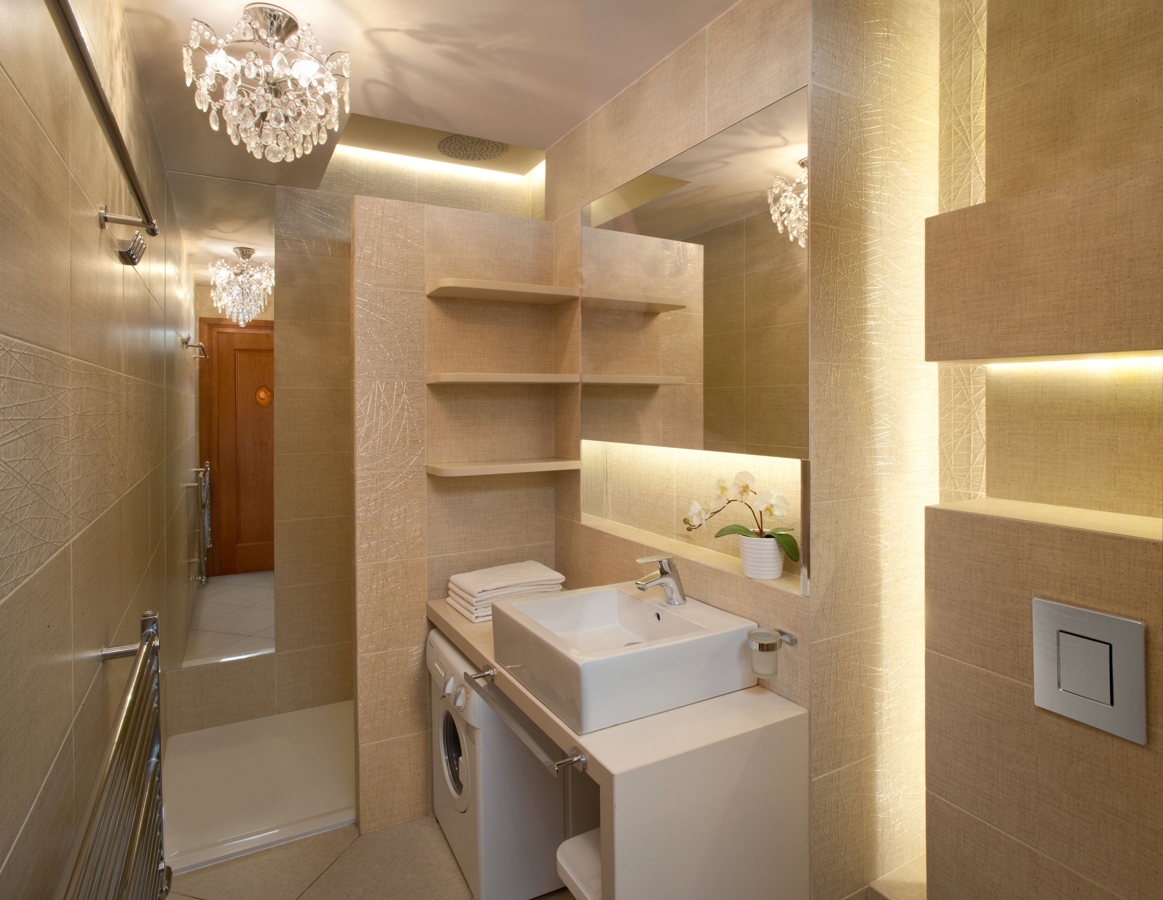Un baño moderno con ducha a ras de suelo, lavadora integrada, tocador con espejo y candelabro.