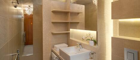 Un baño moderno con ducha a ras de suelo, lavadora integrada, tocador con espejo y candelabro.