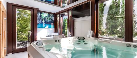 A modern spa area with a hot tub, large windows, and a view of the outdoors.
