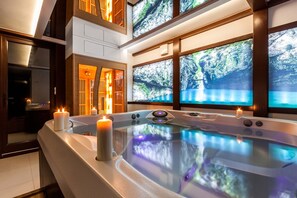 A spa area with a hot tub, candles, and large screens displaying nature scenes. - Parkside Apartments Old Town (Kraków)