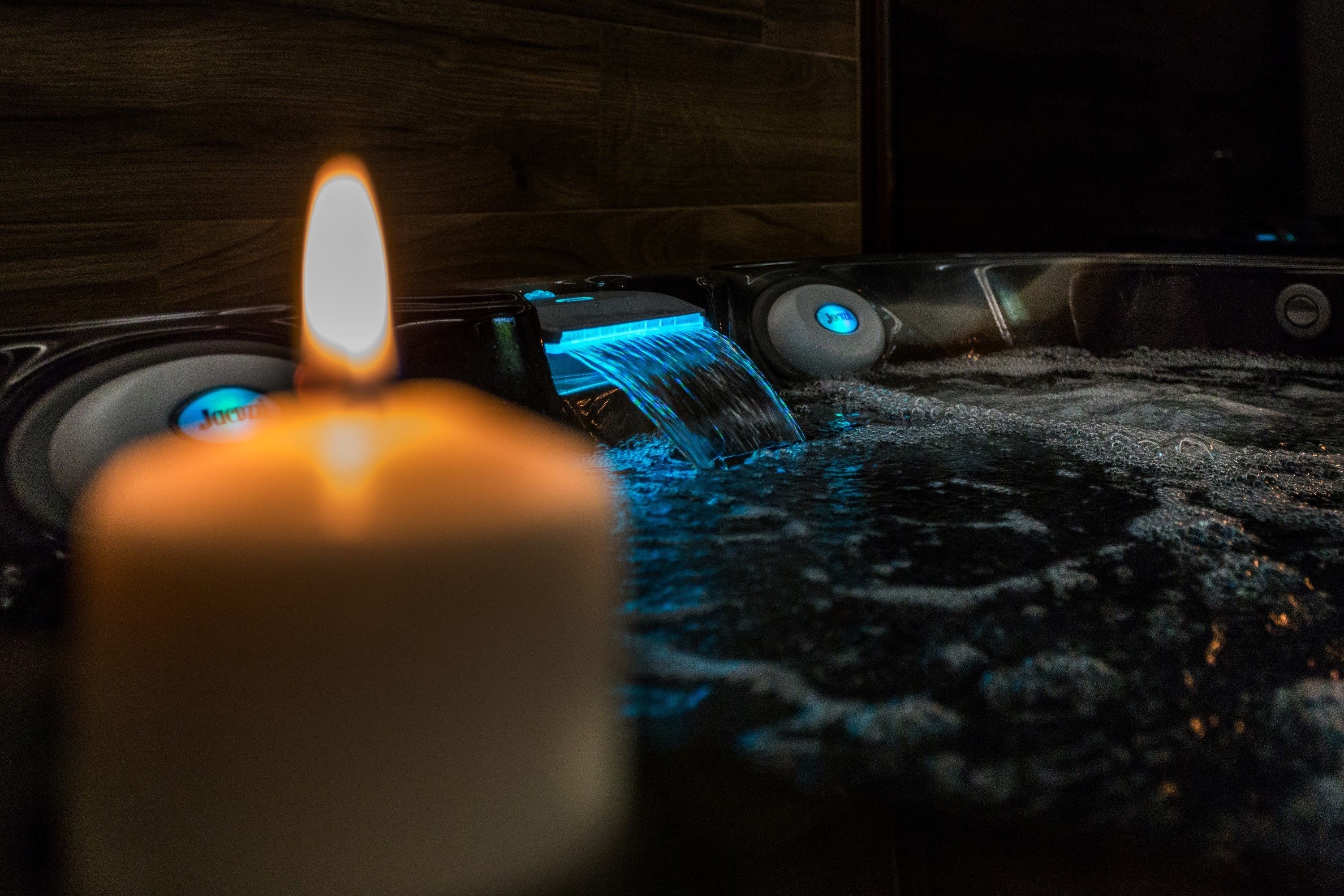 Une bougie avec une flamme allumée, une fontaine illuminée de lumière bleue et un panneau de contrôle avec un éclairage bleu.