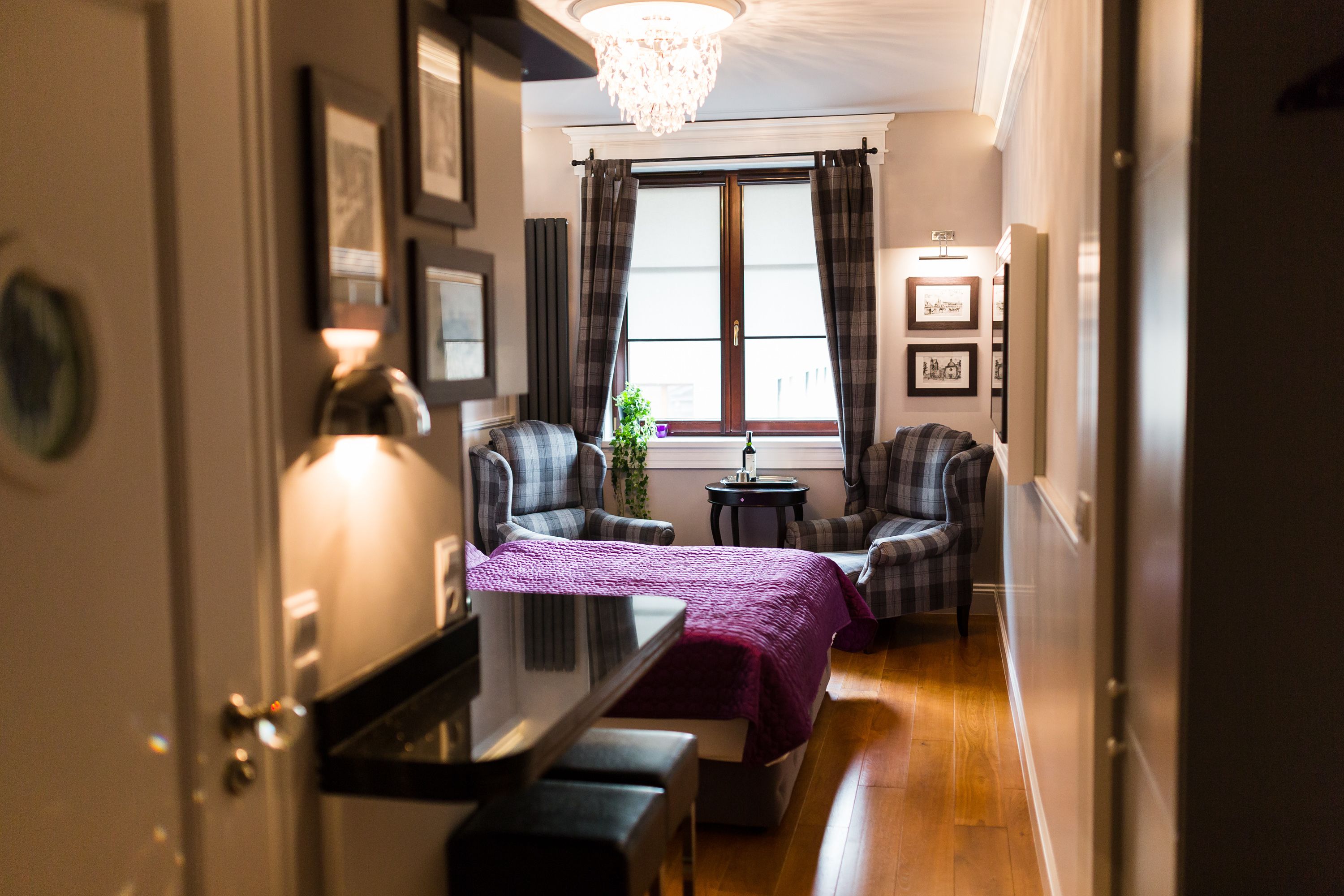 Ett hotellrum med en säng, två fåtöljer, ett litet bord och ett fönster med gardiner.