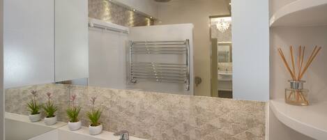 A modern bathroom with a large mirror, a white sink, and a towel rack.
