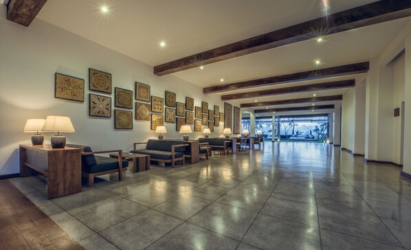 A spacious lobby with a long reception desk, multiple seating areas, and a view of the outdoors.