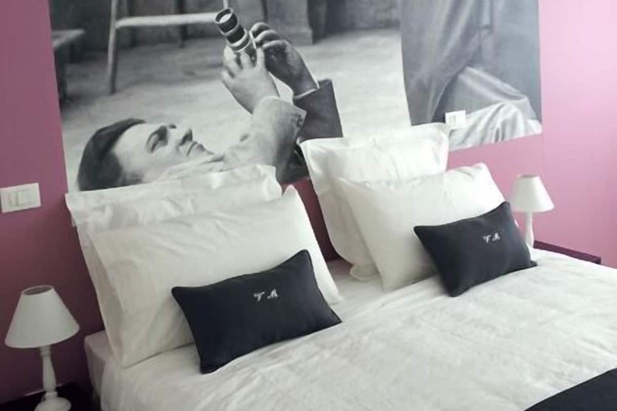 A bedroom with a bed, pillows, a nightstand, and a wall-mounted picture.