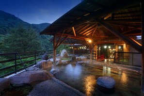 A covered outdoor area with a wooden structure, rocks, and a water feature. - Hotel Sunshine Kinugawa (Nikko)