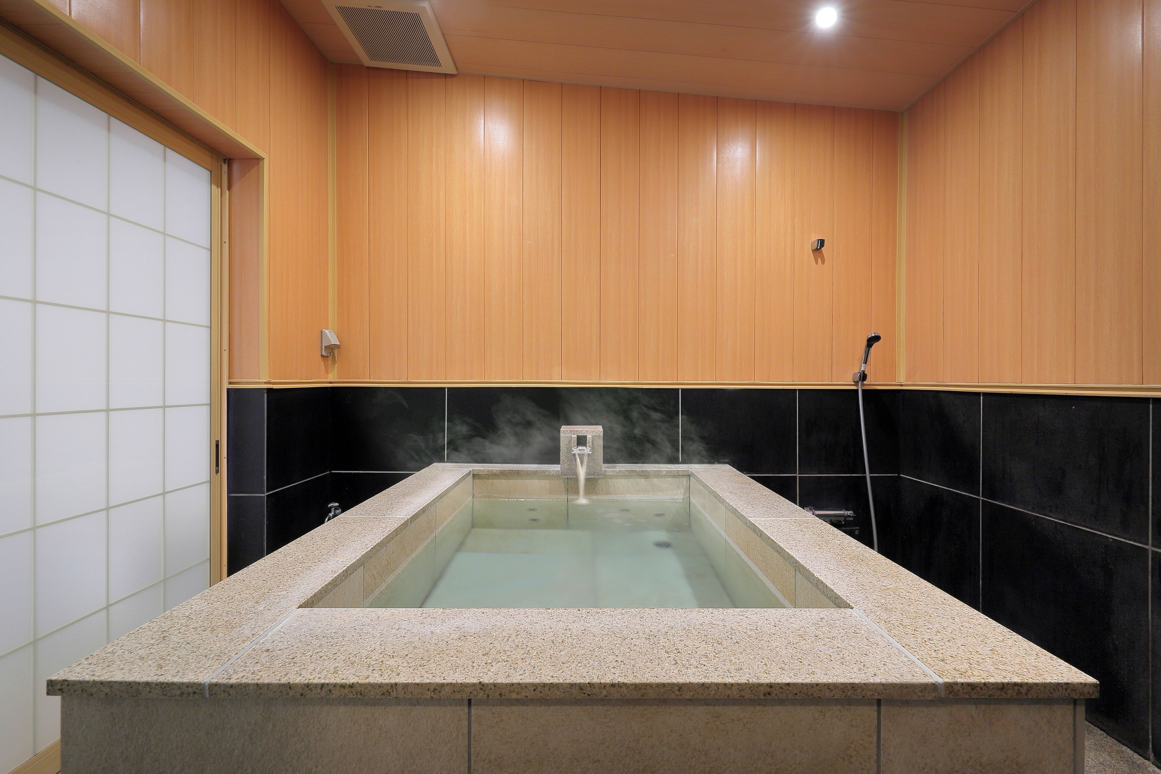 A hot tub with a tiled surround, wooden walls, and a tiled floor.
