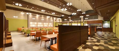 A spacious dining area with multiple tables and chairs, a central seating area, and a patterned floor.