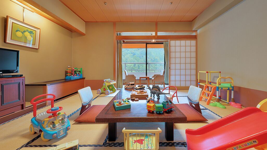 A room with tatami flooring, a television, children's toys, and a sliding door to a balcony.