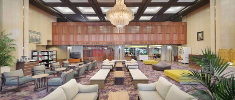 A spacious lobby with a high ceiling, a chandelier, and a variety of seating options including sofas and armchairs.