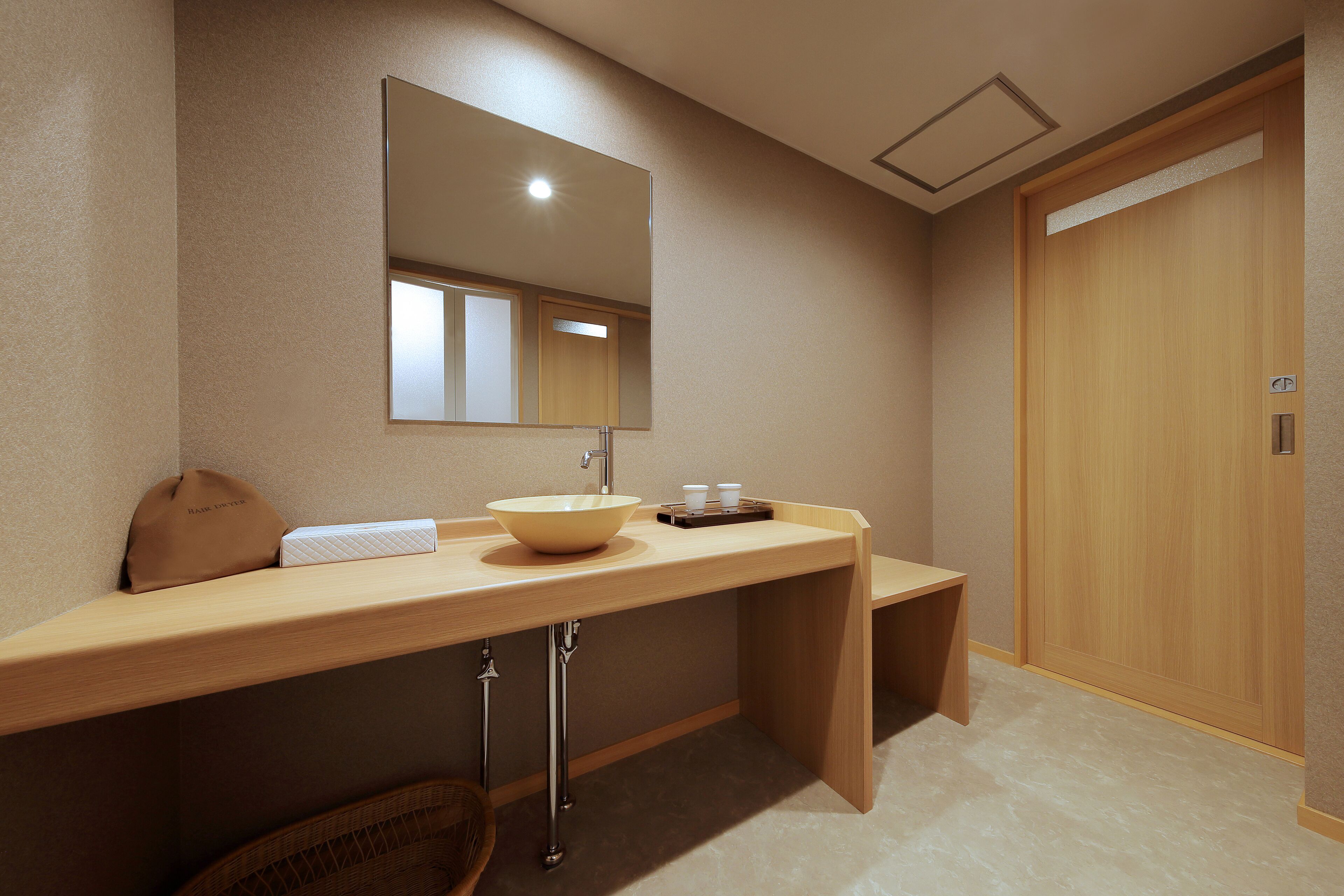 A bathroom with a wooden vanity, a sink, a mirror, and a wooden door.