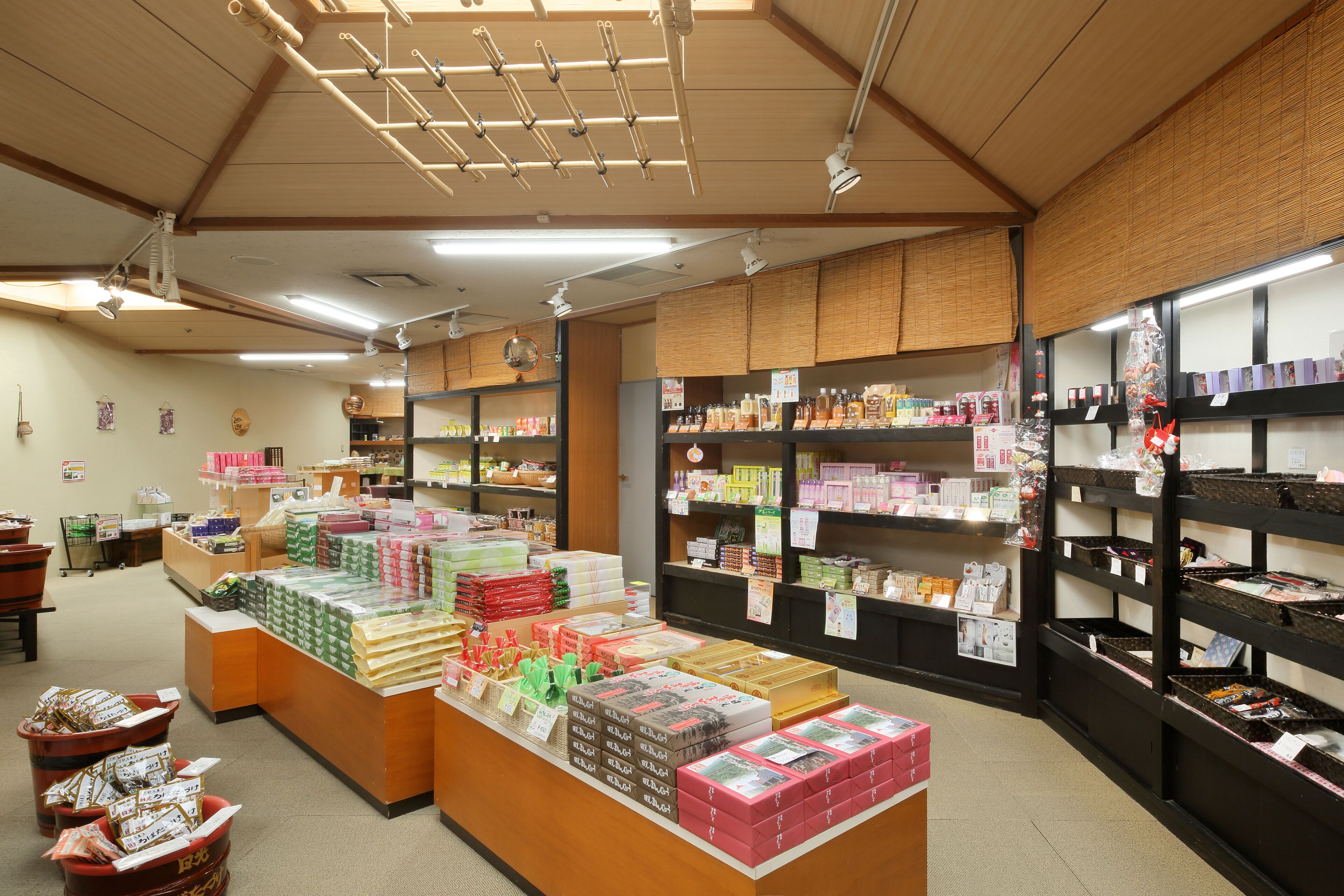 A store interior with shelves stocked with various products, a display counter with boxed items, and baskets on the floor.