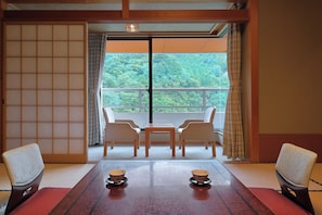 A traditional Japanese room with tatami flooring, a shoji screen, and a view of a forest through a large window. - Hotel Sunshine Kinugawa (Nikko)