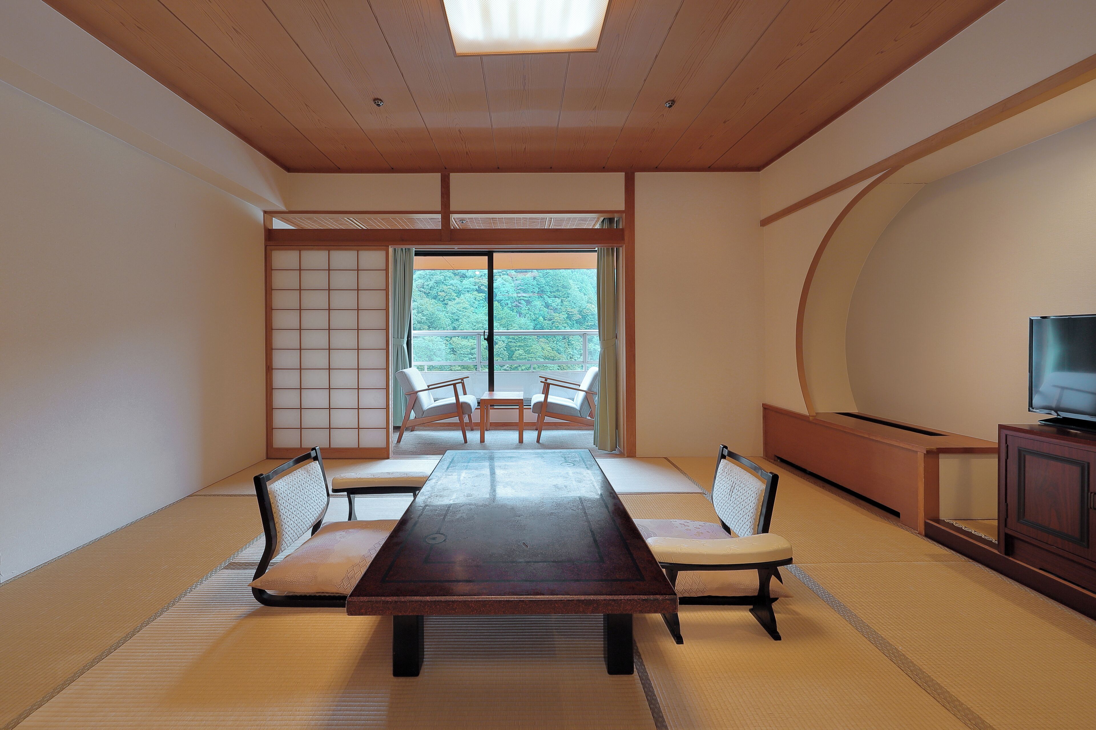 A traditional Japanese room with tatami flooring, a low table, and a TV on a wooden cabinet.