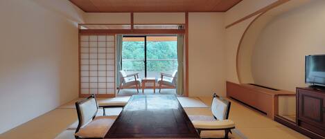 A traditional Japanese room with tatami flooring, a low table, and a TV on a wooden cabinet.