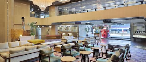A spacious lobby with a high ceiling, a chandelier, and a variety of seating options including sofas and chairs.