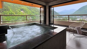 Un baño moderno con una bañera grande, una silla blanca y vistas a un paisaje montañoso.