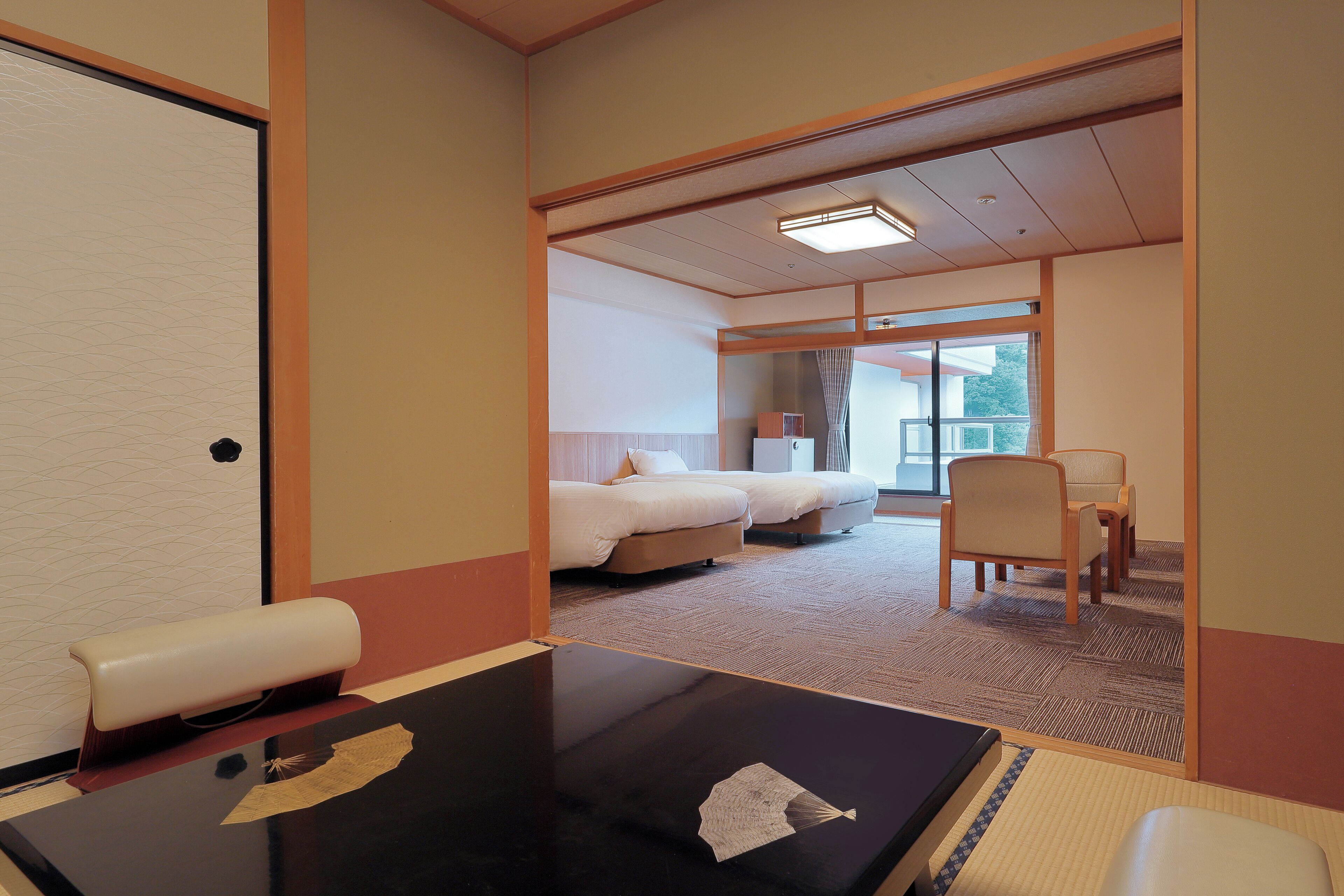 A hotel room with a bed, a desk, and a chair. There is a window with a view of the outside.