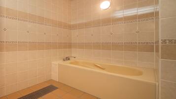 A bathroom with beige tiles, a bathtub, and a shower area.