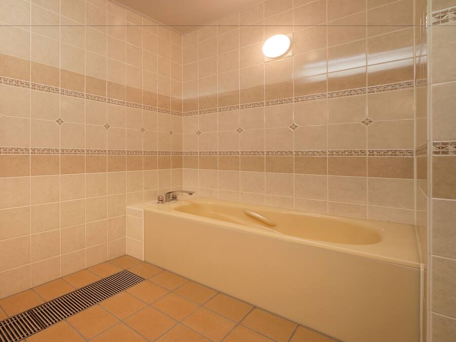 A bathroom with beige tiles, a bathtub, and a shower area.
