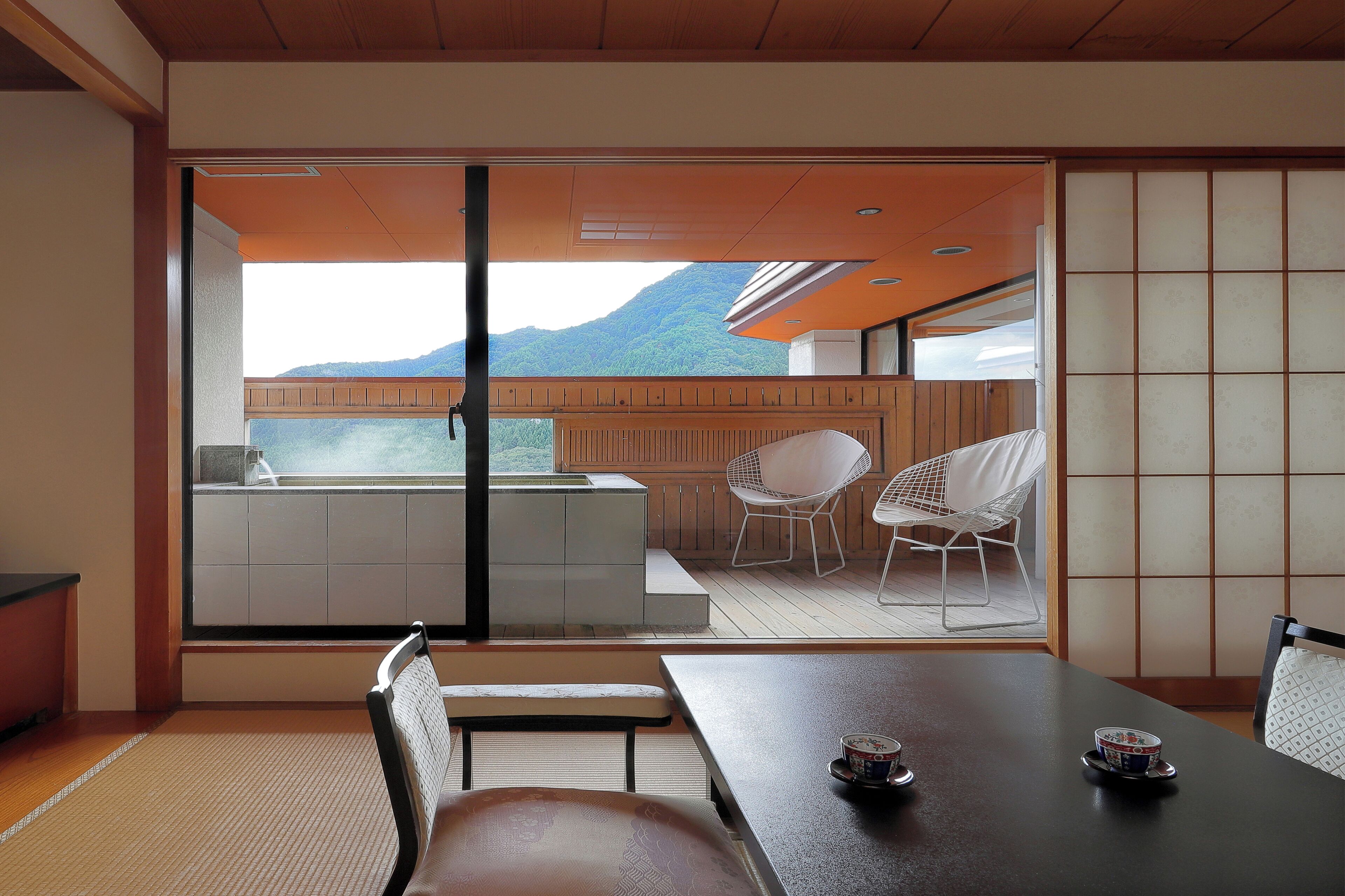 A modern interior with a dining area, a view of a mountain, and traditional Japanese sliding doors.