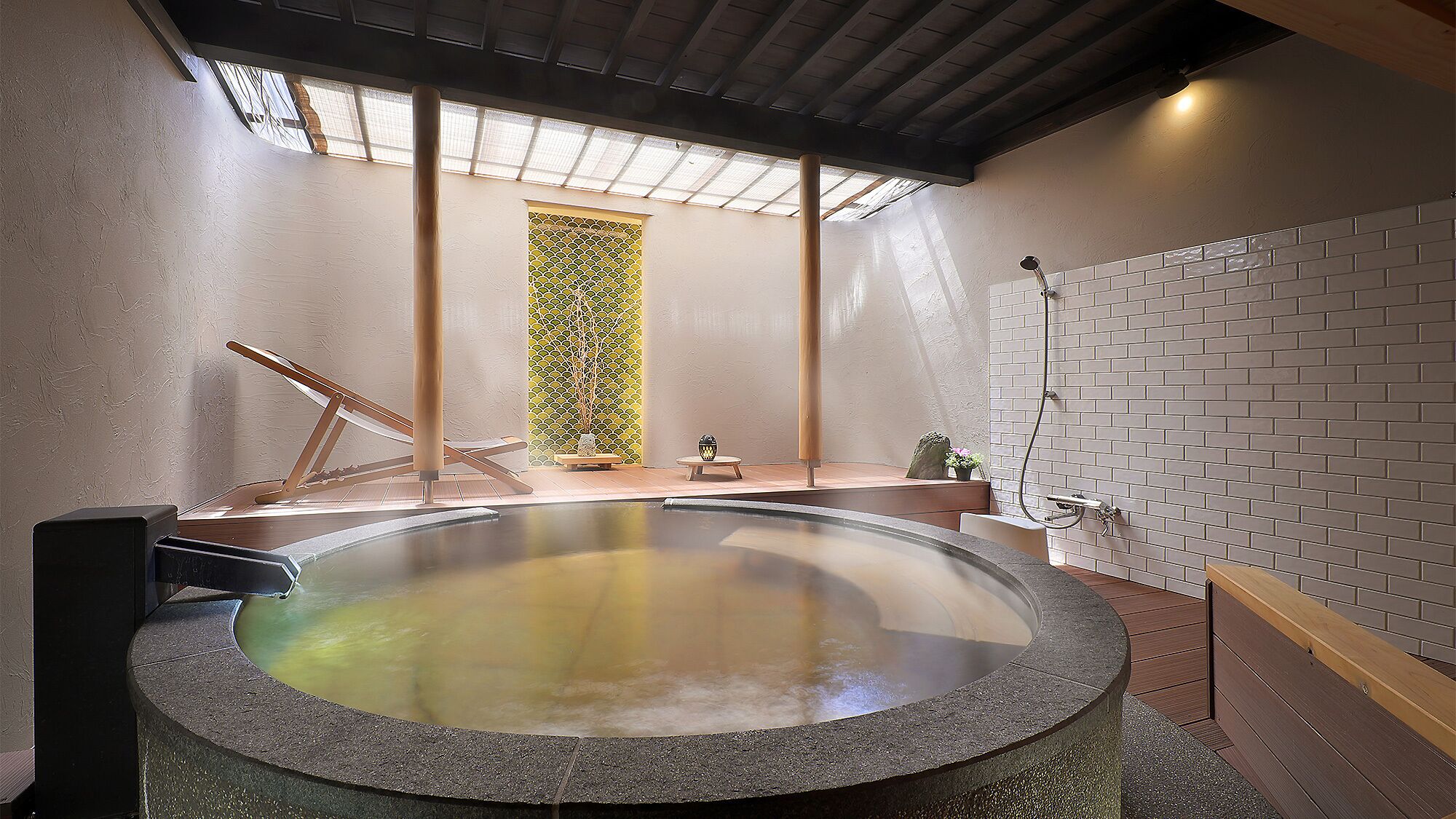 A hot tub with a wooden bench, a small table with a decorative item, and a wall with a patterned design.