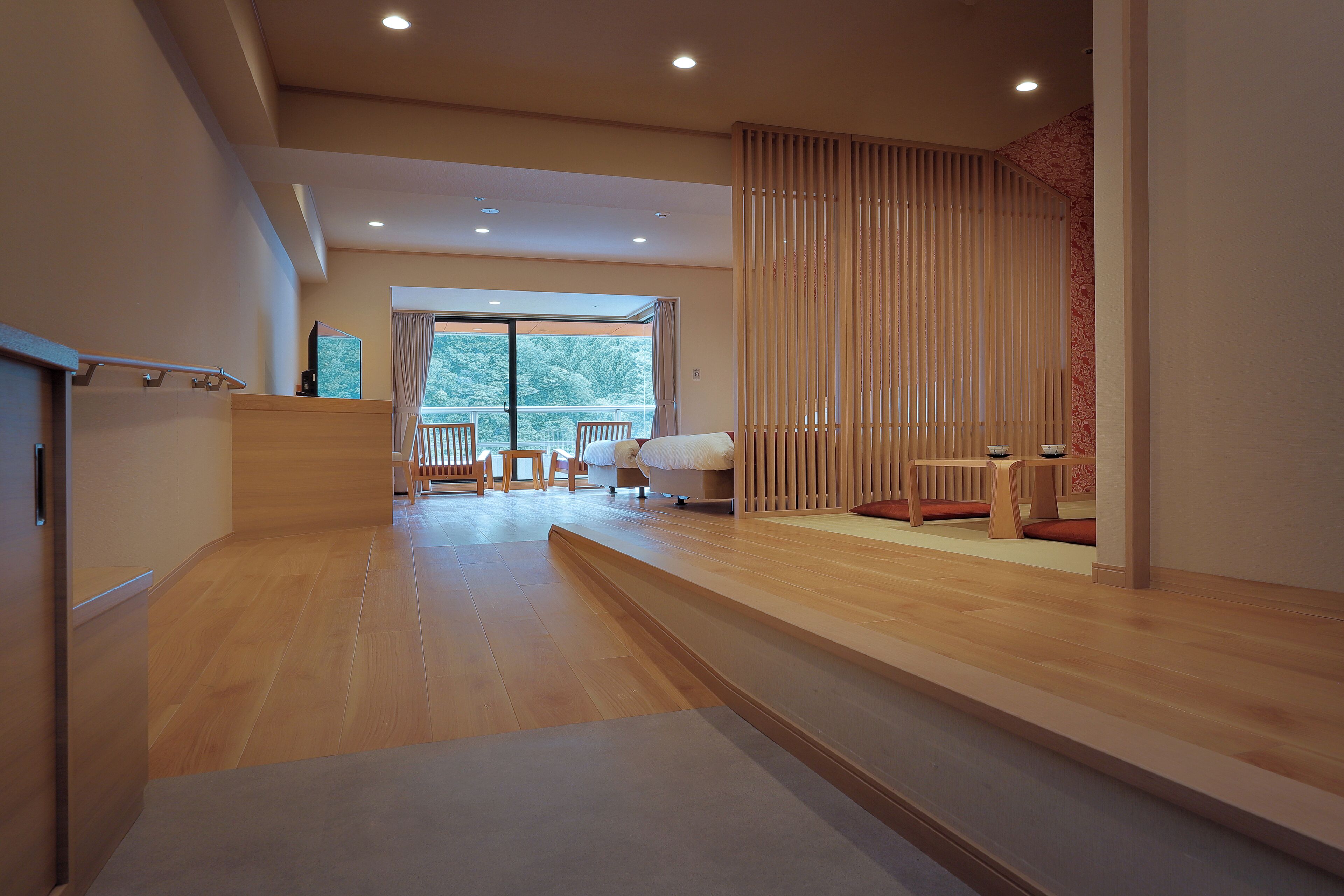 A modern hotel room with a wooden floor, a balcony with a view, and a sliding door.