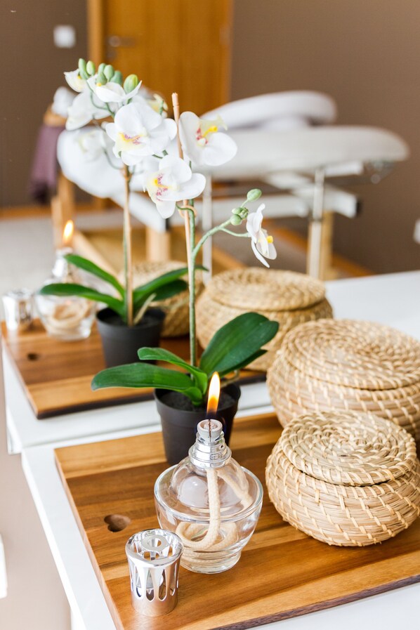Una bandeja de madera con una orquídea en maceta, una botella de vidrio y cestas tejidas.