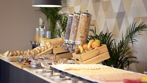 A buffet setup with various food items and containers, including bread, fruits, and condiments.