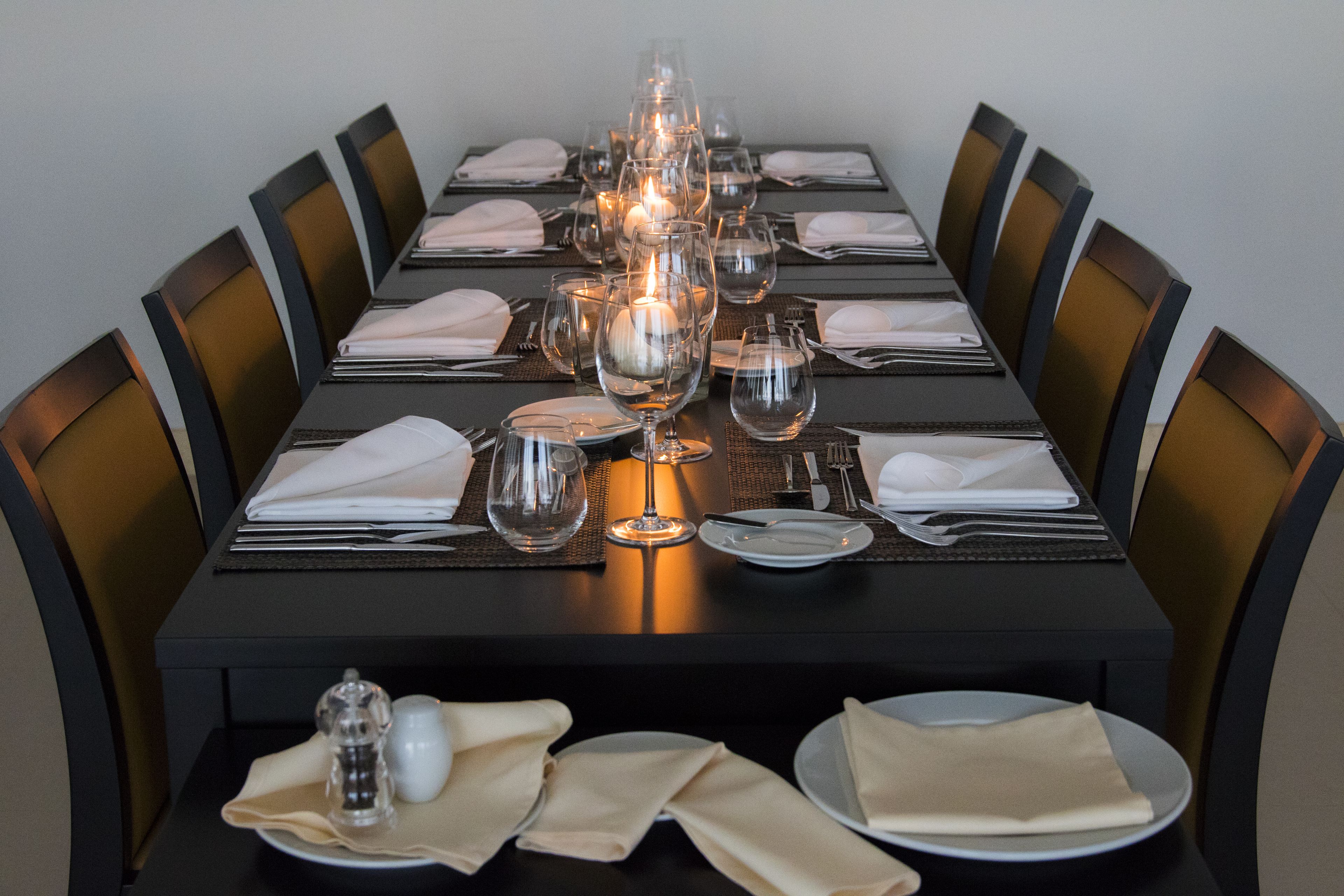 Una mesa de comedor lista para una comida, con varias copas de vino, platos y cubiertos.